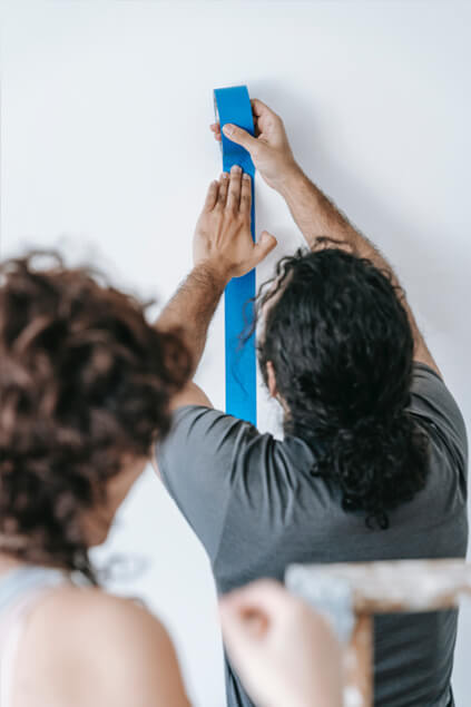 man sticking scotch tape on the wall